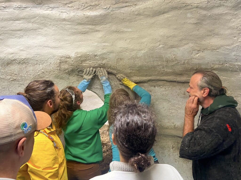 Participants qui modèlent à la main le mur intérieur d’une Kerchanvre en chaux-chanvre